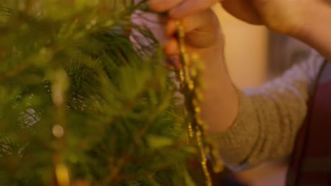 Nahaufnahme-eines-Mannes,-der-einen-Schneeflockenschmuck-auf-einen-Weihnachtsbaum-legt