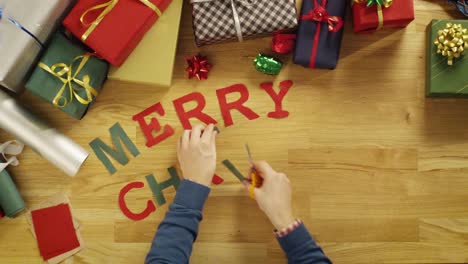 Vista-superior-Time-lapse-de-un-corte-de-hombre-de-letras-para-las-palabras-\"Feliz-Navidad\"-y-poner-en-la-mesa-con-regalo-envuelto-cajas-de-madera.