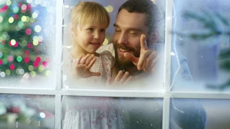 Am-Heiligabend-sucht-Vater-und-seine-Cute-Daughter-durch-das-Schneewittchen,-Frozen-Window-und-Smile.