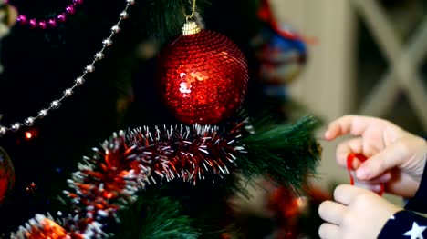Primer-plano-de-las-manos-de-niña-de-niño-están-decorando-un-árbol-de-Navidad-con-brillantes-coloridos-juguetes-de-Navidad,-bolas