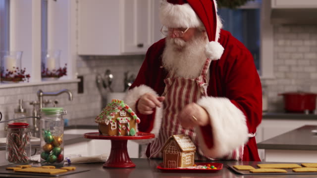 Santa-Claus-in-kitchen-decorating-gingerbread-house