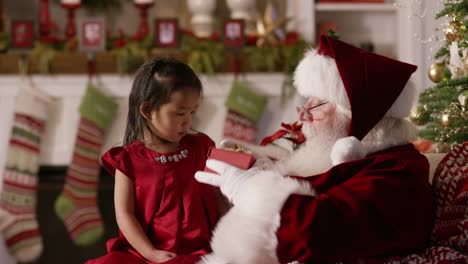 Santa-Claus-öffnet-ein-Geschenk-mit-jungen-Mädchen