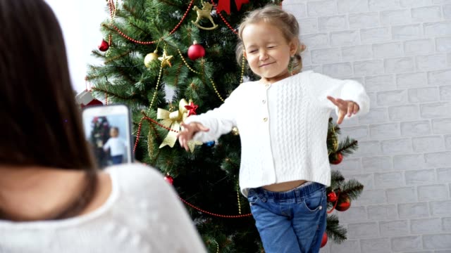 Fröhliches-kleines-Mädchen-tanzen-und-spielen-die-Affen-in-der-Nähe-von-Christmas-tree