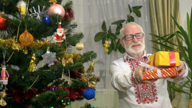 Viejo-lindo-tiene-que-regalos-de-Navidad-cerca-del-árbol-de-Navidad