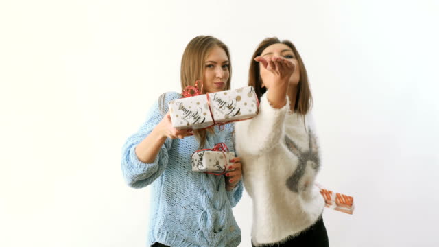 Two-pretty-girls-dances-and-gives-presents-to-each-other-at-white-background