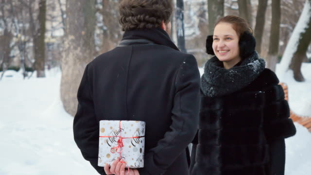 Handsome-man-presents-the-gift-to-the-woman-in-winter-park