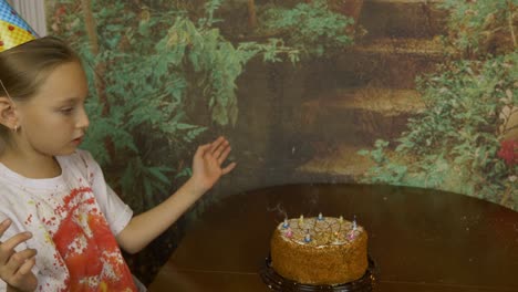 Daughter-with-father-celebrate-birthday.-Girl-put-out-all-candles-on-cake.-Smoke-streams-over-the-extinguished-candles.-Girl-disperses-the-smoke-with-her-hands.