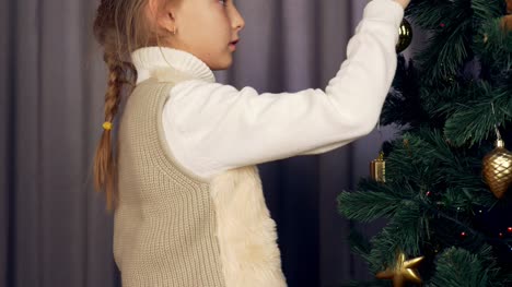 Kaukasisches-Mädchen-halten-dekorative-gold-und-Weiterleitungen-golden-Ball-zum-Weihnachtsbaum.-Junge-Mädchen-bereit,-Weihnachten-und-Neujahr-mit-Weihnachtsschmuck-zu-feiern.