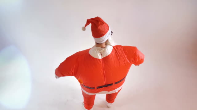 Ein-Künstler-in-einem-aufblasbaren-Santa-Kostüm-grüßt-den-Betrachter.