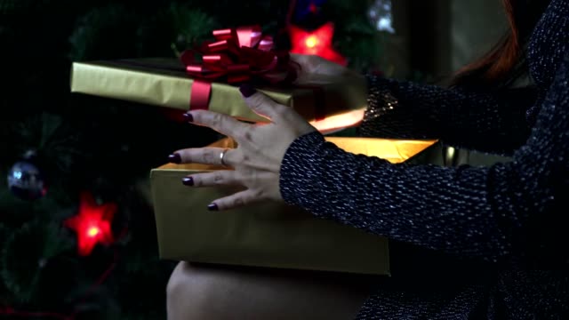 La-chica-abre-un-regalo-junto-al-árbol-de-Navidad.