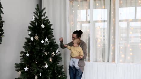 Baby-Junge-mit-Mutter-schmückt-den-Weihnachtsbaum
