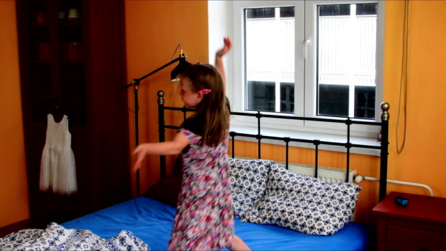 Niedliche-kleine-Mädchen-tanzt-auf-einem-Bett.-Slow-Motion.-Kindheit-Konzept