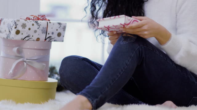 Chica-joven-se-sienta-en-el-piso-cerca-de-regalos-de-Navidad-y-lee-el-libro