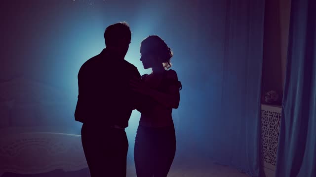 Young-couple-dancing-latin-music.-Silhouette-couple-ballroom.-Smoke