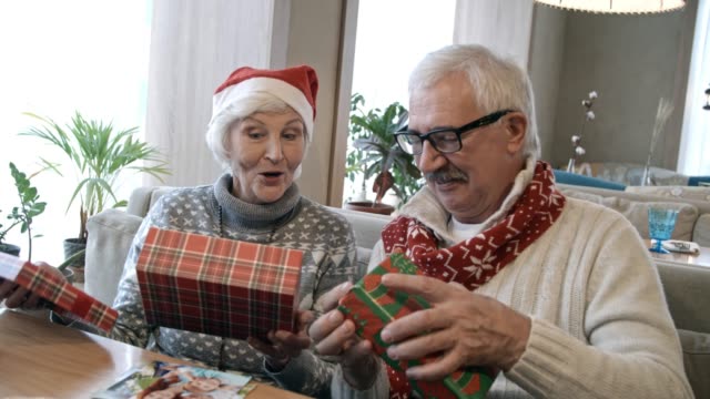 Älteres-Paar-Eröffnung-Weihnachtsgeschenke-an-Urlaub-Abendessen-im-Cafe