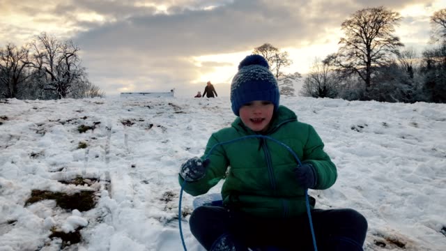 Young-boy-falling-off-a-snowy-sledge