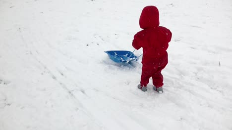 Little-girl-walking-with-her-sledge-in-the-winter-time