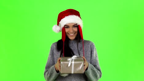 Muchacha-hermosa-de-Santa-sonriente-sosteniendo-un-regalo-de-Navidad-a-la-cámara