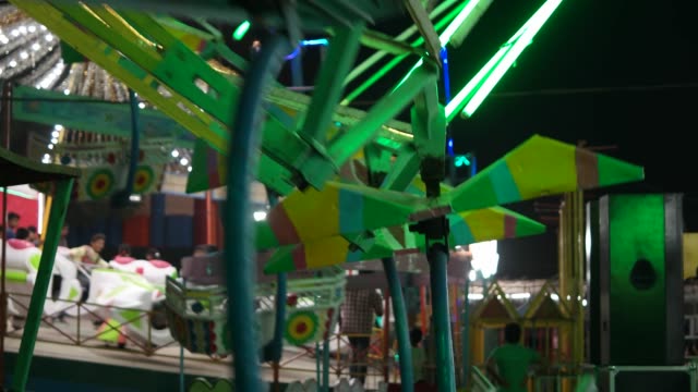 Carnival-with-ferris-wheel,-bright-colourful-lights,-car-carousel-at-night-closeup