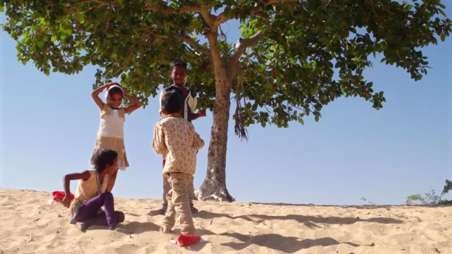 WS-Kinder-umarmt-umarmt-und-kauern-in-Sand-der-Wüste-mit-Santa-Hüte-unter-einem-Baum