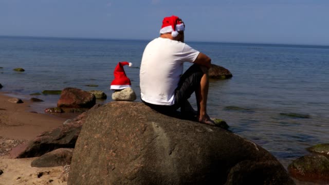 Hombre-con-sombrero-de-Santa-Claus-relajante-cerca-del-mar