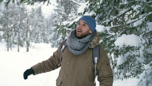 Carefree-Man-Enjoying-Snowfall-From-Tree