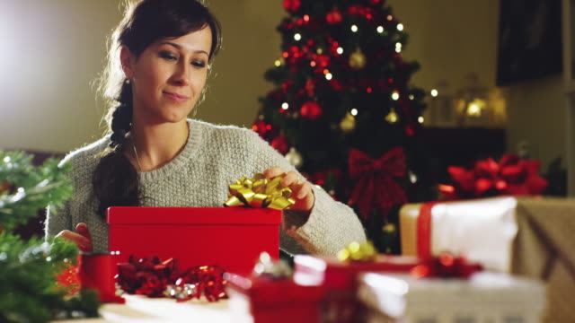 Mädchen-mit-weihnachtsmütze-macht-Wünsche-und-öffnet-ein-Weihnachts-Geschenk-Paket.-Konzept-der-Feiertage-und-Neujahr.-Das-Mädchen-freut-sich-und-lächelt-mit-Weihnachts-Geschenk-in-der-hand.