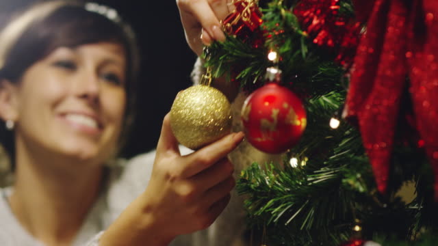 die-Hand-einer-Person-schmückt-den-Weihnachtsbaum-mit-den-goldenen-und-roten-Kugeln.-Konzept-des-Wartens-auf-Weihnachten-und-Neujahr.