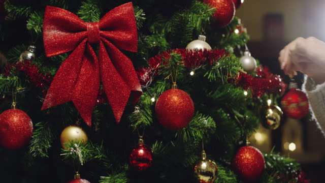 die-Hand-einer-Person-schmückt-den-Weihnachtsbaum-mit-den-goldenen-und-roten-Kugeln.-Konzept-des-Wartens-auf-Weihnachten-und-Neujahr.