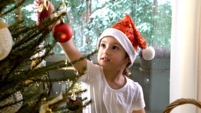 Kleine-süße-Mädchen-mit-ihrer-Mutter-schmücken-den-Weihnachtsbaum