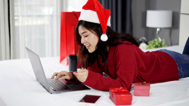 glückliche-Frau-online-shopping-für-Weihnachtsgeschenk-mit-Computer-Laptop-und-Kreditkarte-auf-einem-Bett