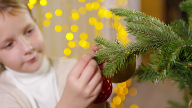 Kleines-Mädchen-hängen-leuchtende-Kugel-am-Weihnachtsbaum