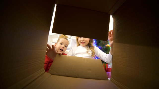 Los-niños-felices-abren-la-caja-cerca-del-árbol-de-Navidad