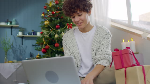 Glückliche-lockiges-Frau-arbeiten-am-Laptop-zu-Weihnachten