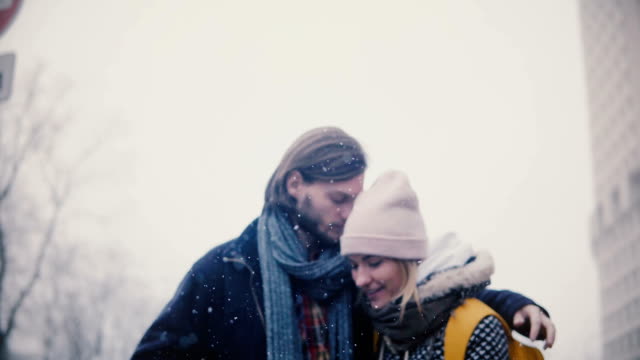 Happy-relaxed-young-romantic-couple-in-casual-warm-clothes-walk-together,-hug-and-kiss-on-a-snowy-winter-Christmas-day.