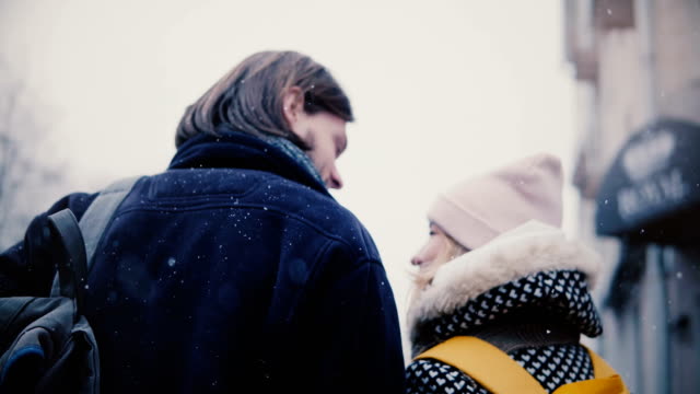 Back-view-happy-relaxed-young-romantic-couple-in-casual-warm-clothes-walk-together-and-kiss-on-a-snowy-cold-winter-day.