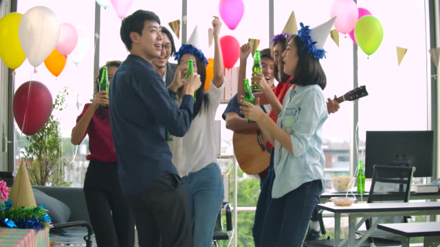 Team-of-young-people-dancing-and-having-fun-celebrate-with-toast-and-clinking-raising-glasses-in-their-office.-Slow-motion-shot