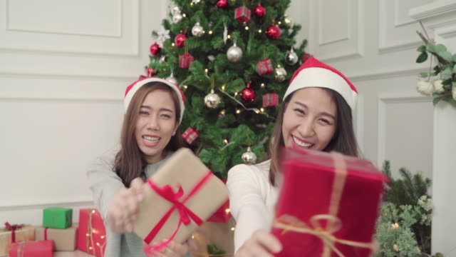 Group-of-cheerful-happy-young-Asian-women-giving-christmas-gifts-to-each-other-in-her-living-room-at-home-in-Christmas-Festival.-Lifestyle-women-celebrate-Christmas-and-New-year-concept.