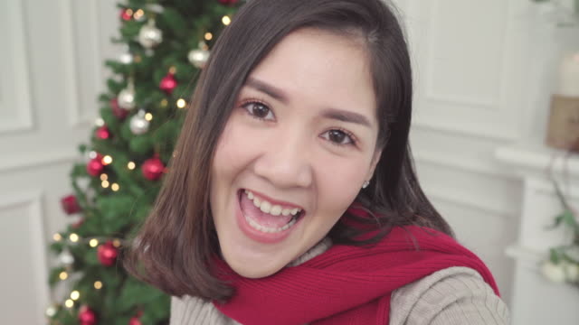 Fröhlich-glücklich-junge-Asiatin-mit-Smartphone-Selfie-mit-Weihnachten-Baum-schmücken-ihr-Wohnzimmer-zu-Hause-in-Christmas-Festival.-Lifestyle-Frau-feiern-Weihnachten-und-Neujahr-Konzept.