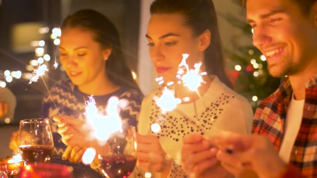 happy-friends-with-sparklers-having-christmas-dinner-at-home