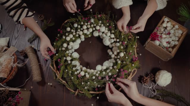 top-view-Christmas-wreath-on-craft-background,-pretty-women-hands-preparing-Christmas-Evergreen-Tree-Wreath