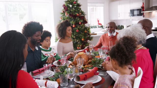 Multi-generación-mixta-familia-carrera-sentado-en-la-mesa-de-la-cena-de-Navidad-las-manos-y-diciendo:-gracia,-enfoque-selectivo