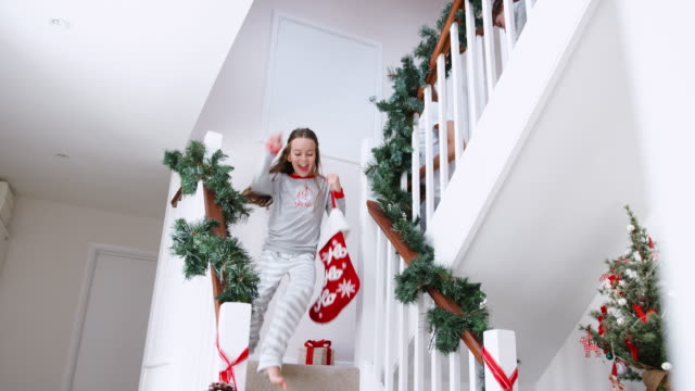 Familia-muy-contento-vistiendo-pijamas-bajando-escaleras-con-medias-en-la-mañana-de-Navidad