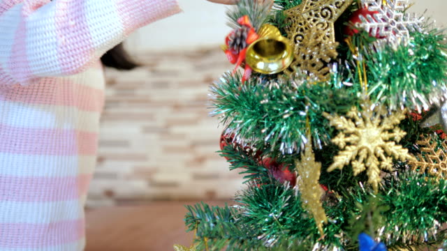 Feliz-niña-asiática-decorando-un-árbol-de-Navidad-con-su-madre