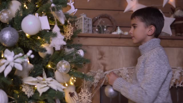 Ein-kleiner-Junge-schmückt-einen-Weihnachtsbaum-mit-einem-schönen-Ball-mit-einer-guten-Stimmung.
