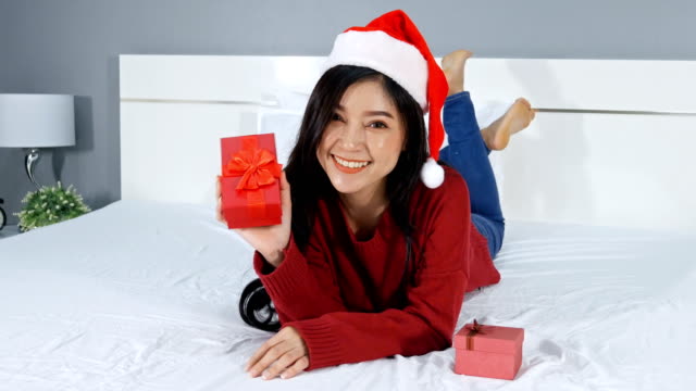 glückliche-Frau-hält-Weihnachtsgeschenk-auf-einem-Bett