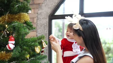 Tochter-von-Mutter-und-Kind-schmücken-den-Weihnachtsbaum-im-Innenbereich.-Closeup-Zeitlupe-Porträt-des-liebenden-Familie,-Frohe-Weihnachten-und-schöne-Feiertage!