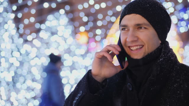 Junger-Mann-am-Telefon-zu-sprechen,-in-der-Weihnachtsnacht-auf-der-Straße