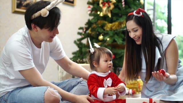 Happy-family-of-mother-father-and-baby-daughter-with-Christmas-tree-at-home.-Closeup-slow-motion-portrait-of-loving-family,-Merry-Christmas-and-Happy-Holidays!