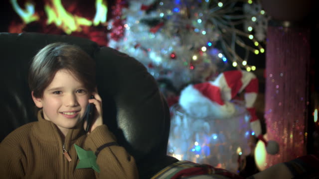 4k-Christmas-and-New-Year-Holiday-Child-Talking-on-Phone-at-Fireplace